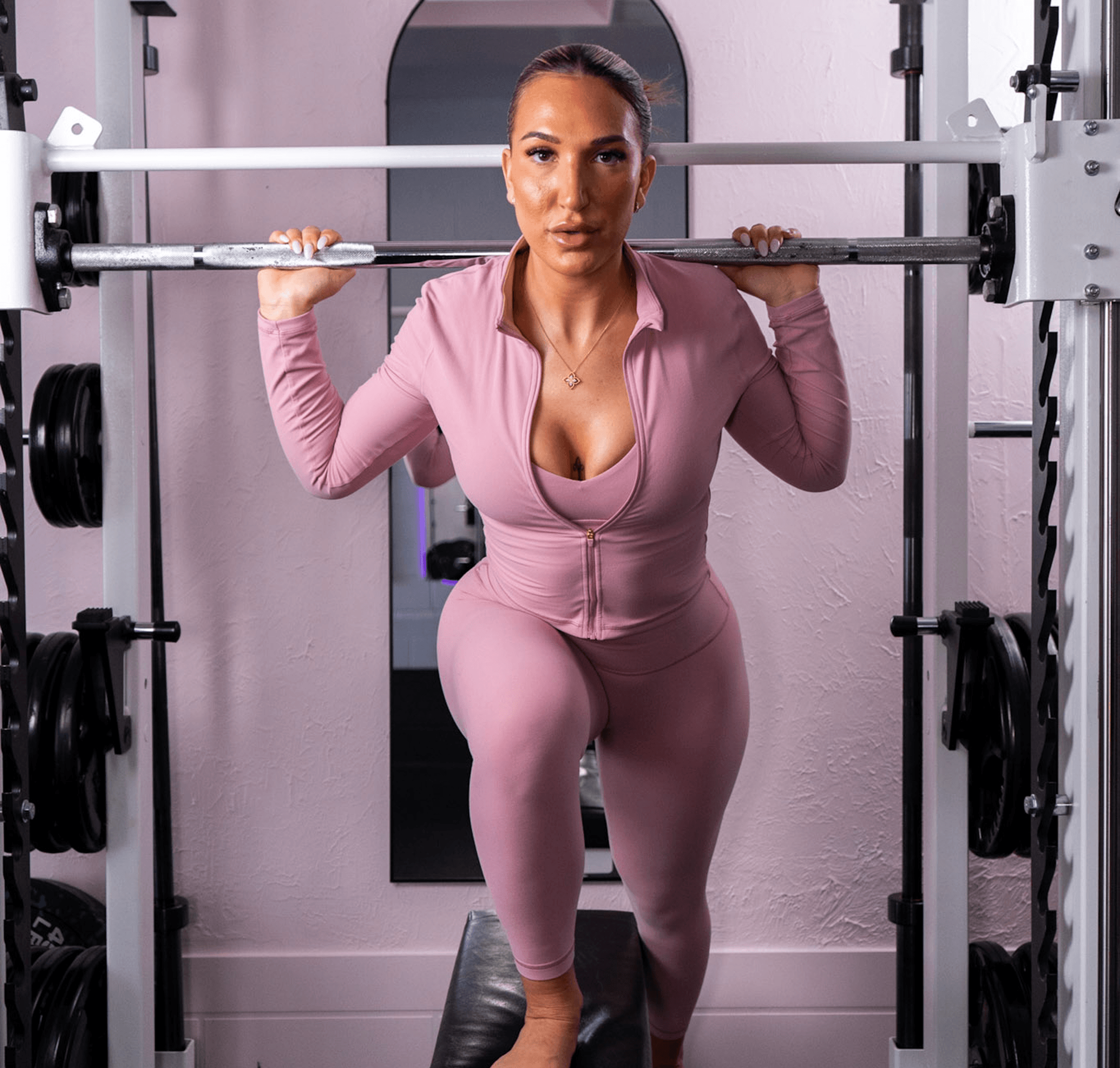 Woman in pink workout clothes using gym equipment